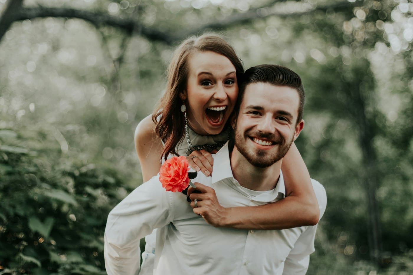 A laughing bride riding piggyback on her groom